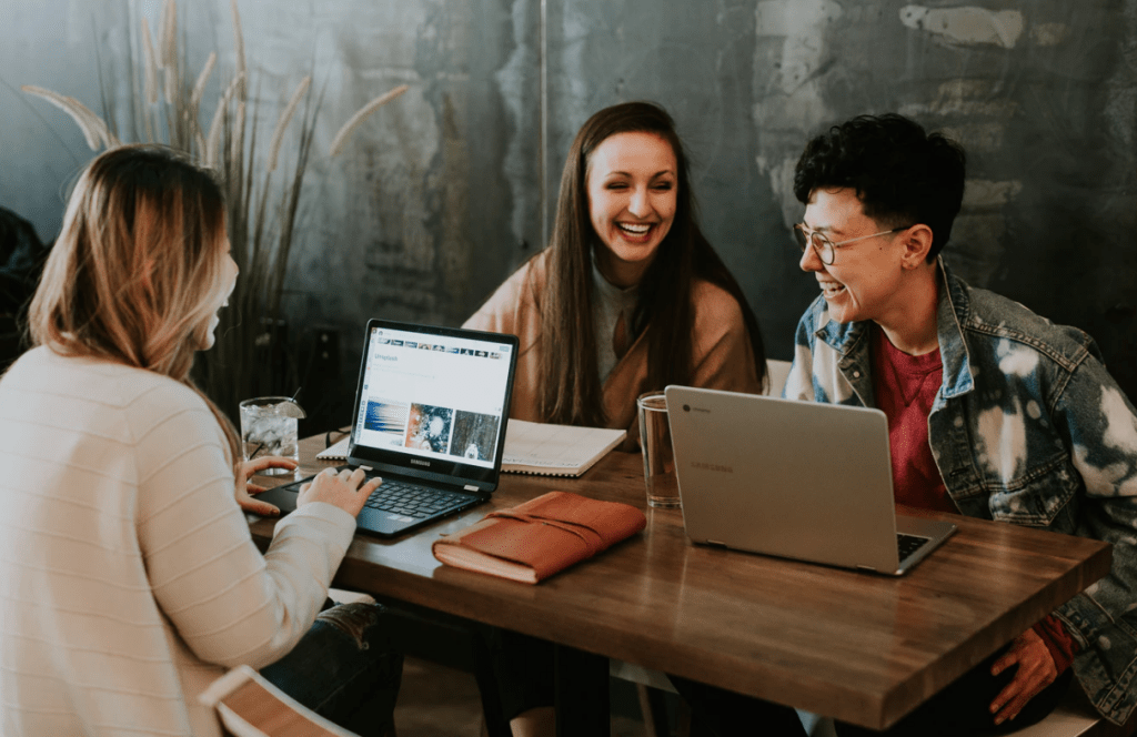summer internship, three young people sitting around table laughing