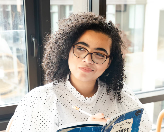 student with book thinking about thesis topic