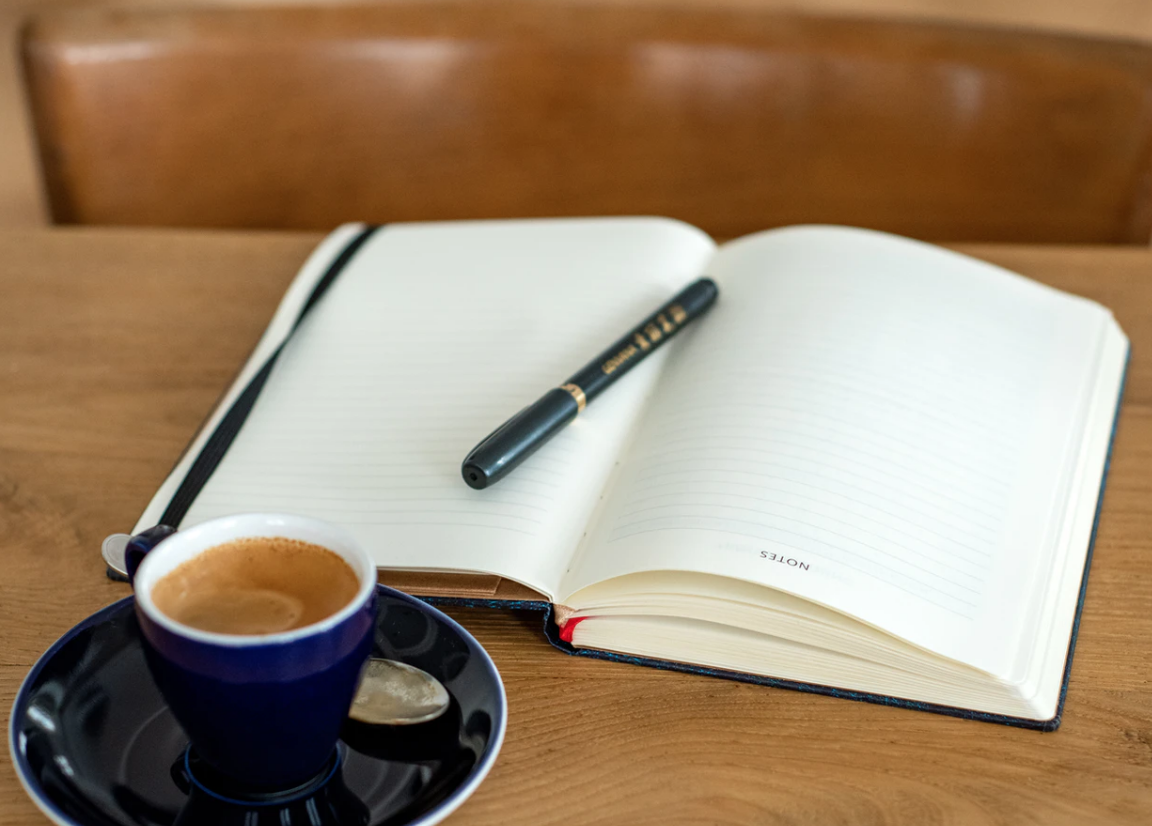 espresso and open notebook with a pen on a wooden table, mothers returning to school