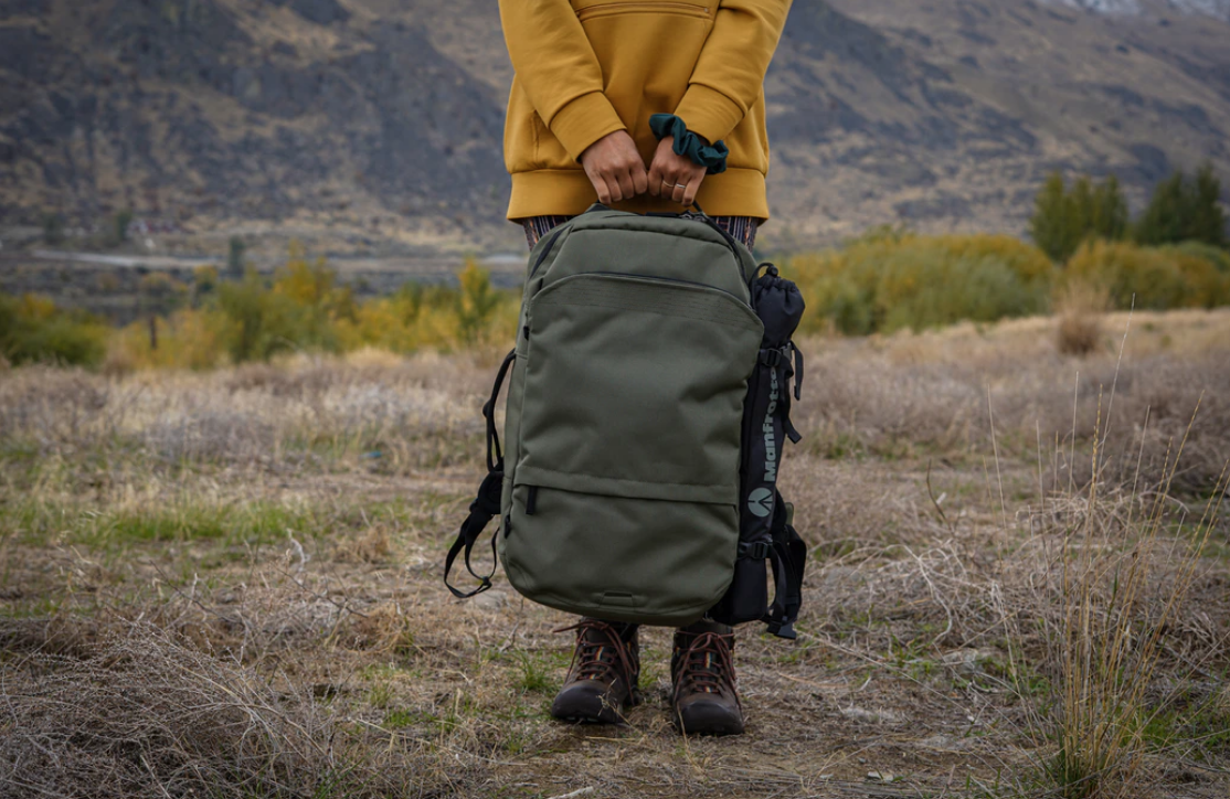 person holding backpack with both hands wearing yellow sweater, choosing a university