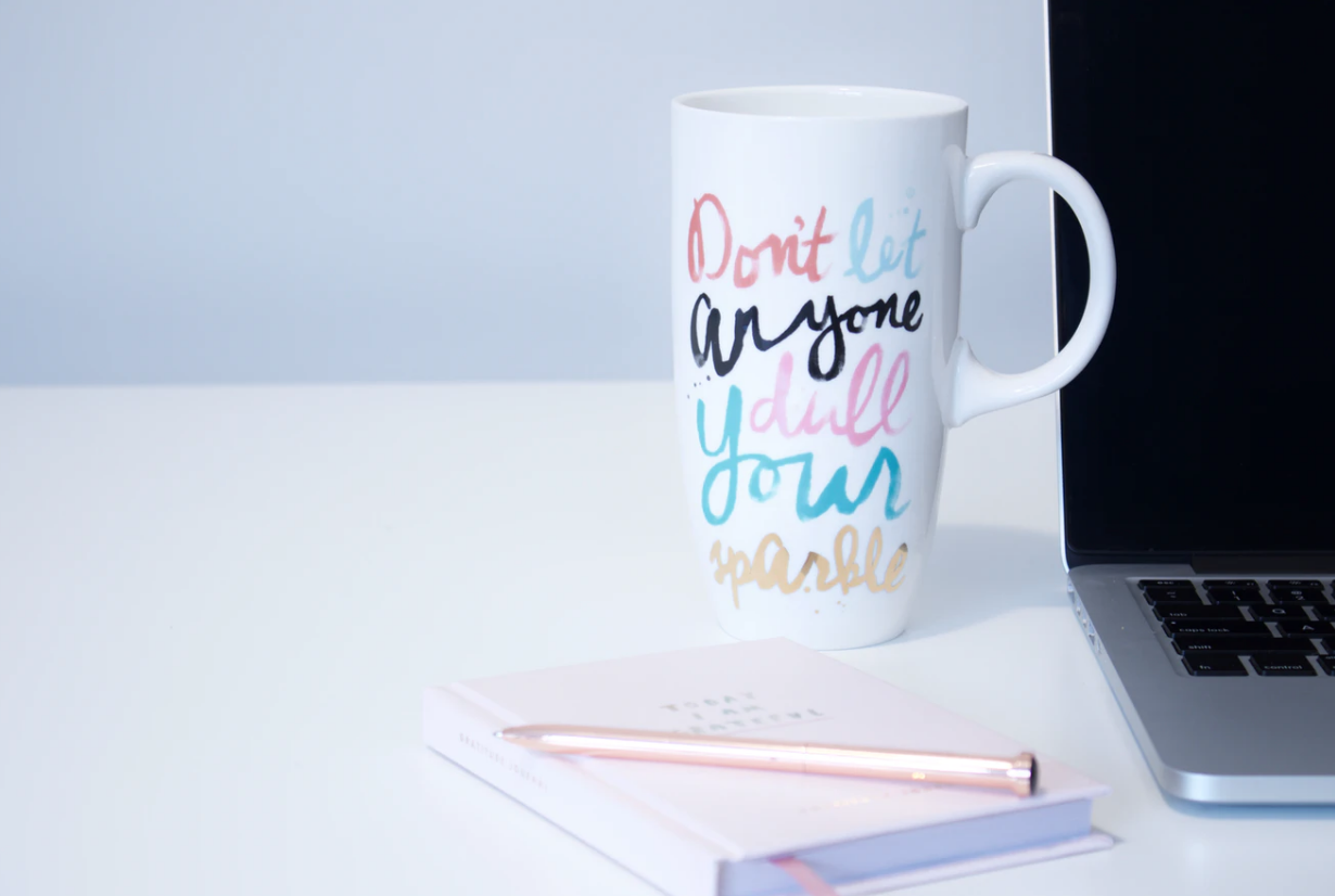 tall coffee mug that reads "don't let anyone dull your sparkle" placed beside notebook, pen, and open laptop, letters of recommendation