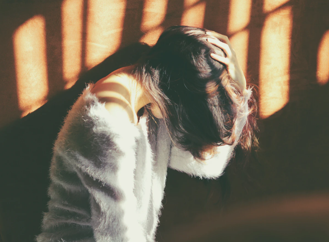 right choice , woman bending forward to cover face with hair and a hand on her head