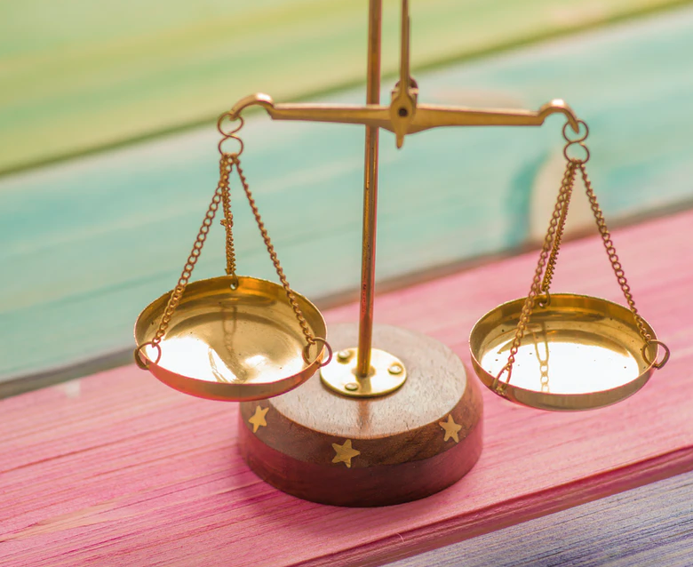 golden scale sitting against rainbow background, costs of post-secondary